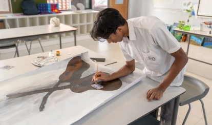 A student paints a realistic image of two guitars on a large canvas